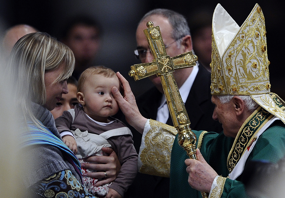 Papa Benedict al XVI-lea mângâie un copil în timp ce părăseşte Bazilica Sfântul Petru de la Vatican, după ce a condus o procesiune de 180 de clerici din Orientul Mijlociu, miercuri, 24 octombrie 2010. 