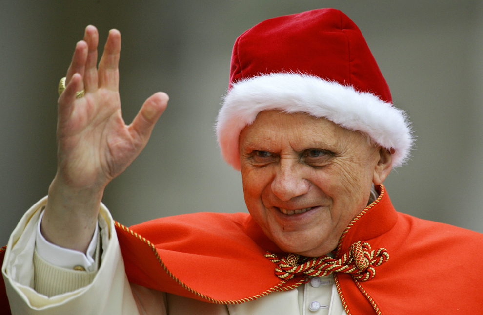 Papa Benedict al XVI-lea, purtând o bonetă din catifea roşie, purtată în mod tradiţional de papi şi denumită “camauro”, salută pelerinii din piaţa Sfântul Petru, în timpul audienţei generale, miercuri, 21 decembrie 2015. 