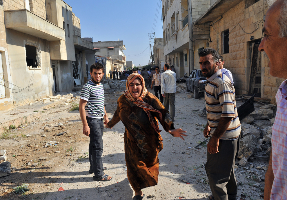 O femeie siriană aleargă printre resturile rămase în urma unui bombardament aerian, în oraşul Azaz, aproape de Alep, centrul rezistenţei antiguvernamentale din nord, miercuri, 15 august 2012. (Bulent Kilic / AFP)
