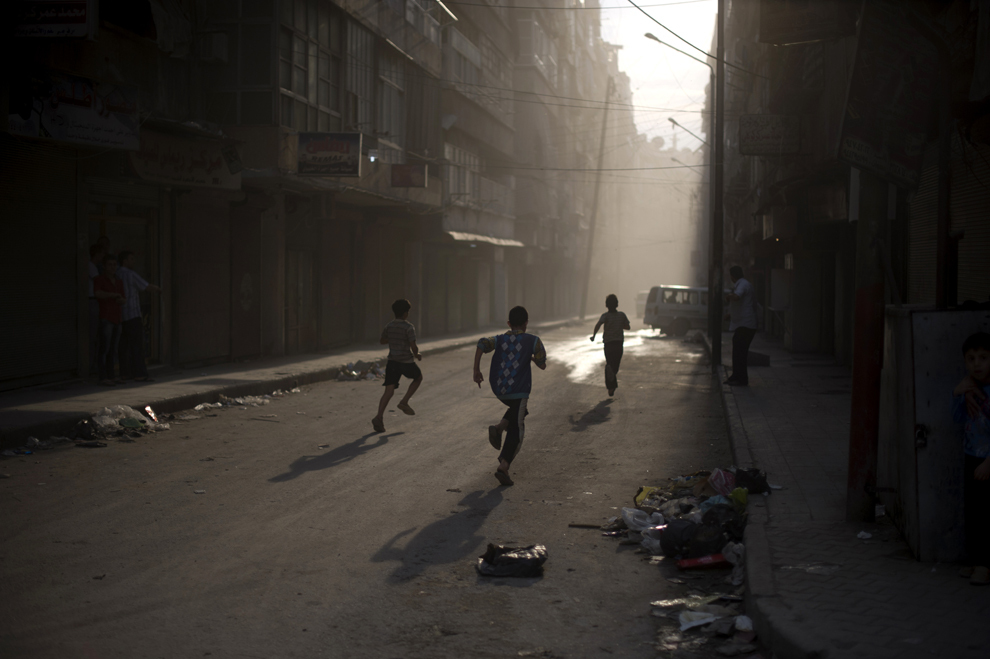 Mai mulţi băieţi sirieni aleargă pentru a se proteja de atacurile cu mortiere, în cartierul lor din Alep, marţi, 9 octombrie 2012. (Zac Baillie / AFP)