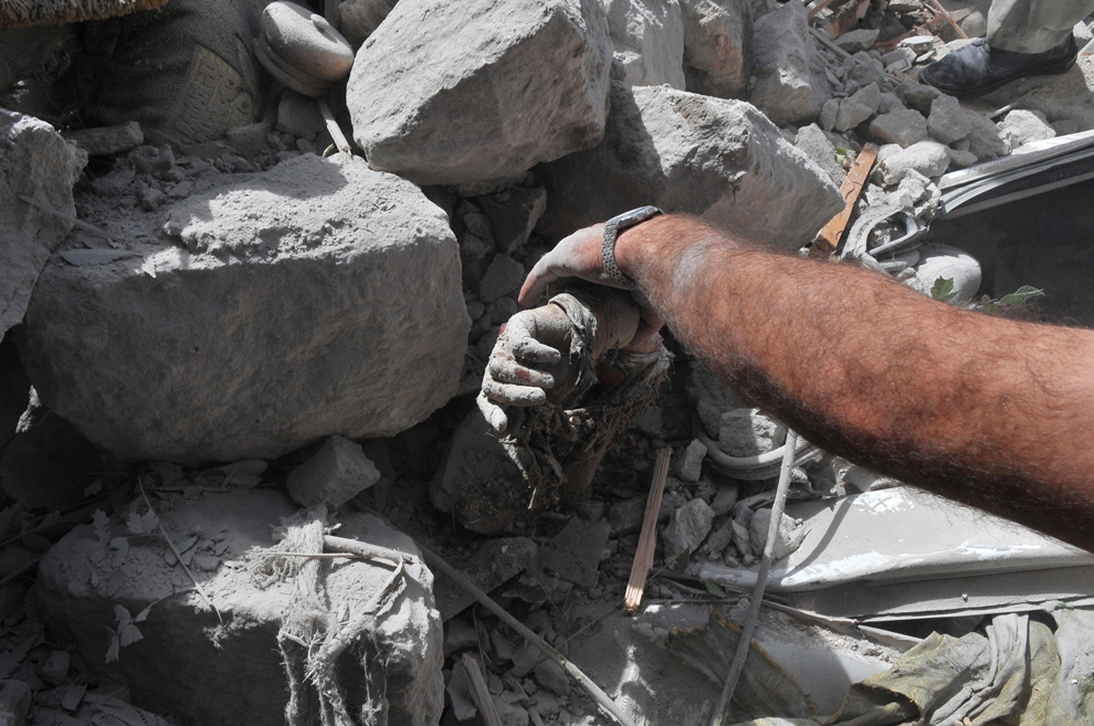 Un sirian trage cadavrul unei victime prinse în ruinele unei clădiri distruse în urma unui atac aerian al forţelor guvernamentale, în Maaret al-Numaan, oraş aflat in nord-vestul Siriei, joi, 18 noiembrie 2012. (Bulent Kilic / AFP)