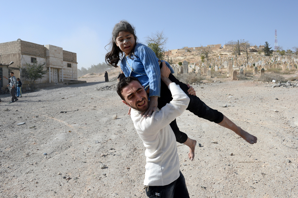 Un bărbat sirian cară o fată rănită în urma unui bombardament aerian al forţelor guvernamentale, în Al-Bab, oraş aflat în nordul Siriei, la 40 de km nord-est de Alep, duminică, 4 noiembrie 2012. (Philippe Desmazes / AFP)