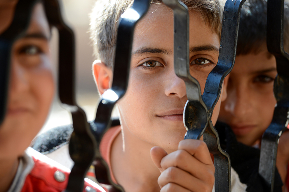 Mai mulţi băieţi sirieni aşteaptă sa primeasca de mâncare în spatele unei uşi de fier, la o şcoala care găzduieşte aproape 140 de refugiaţi, în oraşul Atme din provincia Idlib a Siriei, marţi, 6 noiembrie 2012. (Philippe Desmazes / AFP)