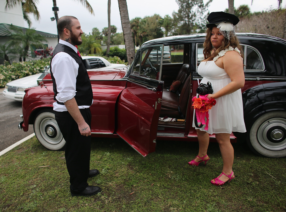 Proaspăt căsătoriţi, Robert şi Ashley Homa pozează lângă un Rolls-Royce, după ce au luat parte la o ceremonie în cadrul căreia 40 de cupluri s-au căsătorit, în West Palm Beach, Florida, joi, 14 februarie 2013. 