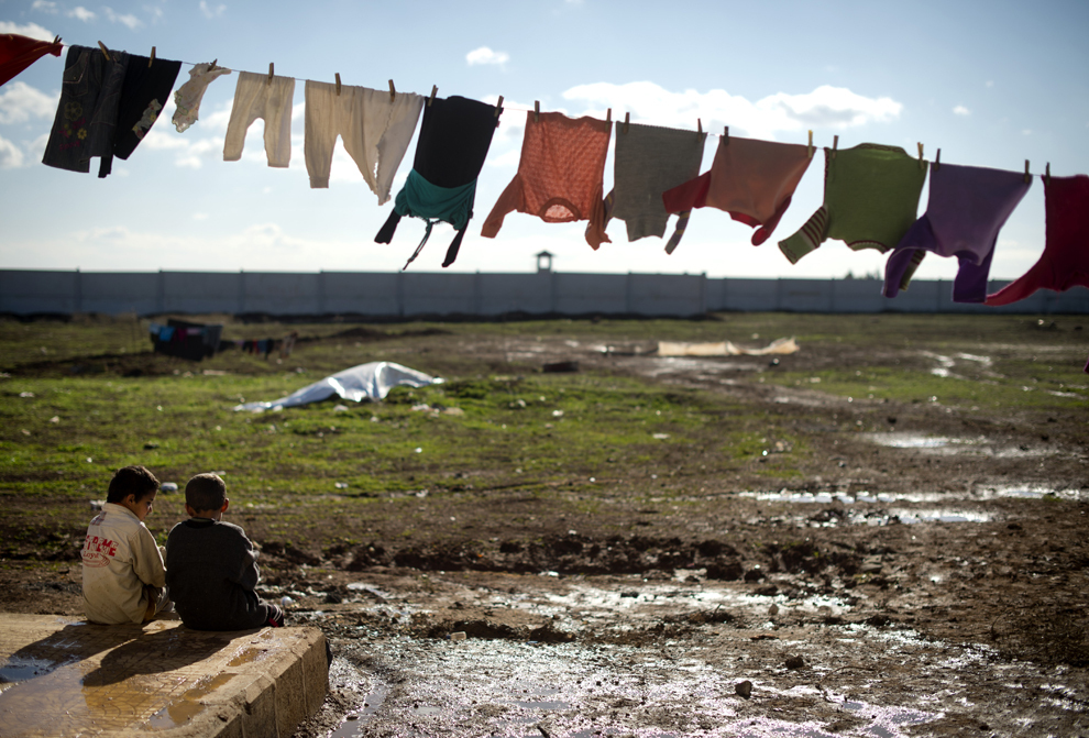 Doi  copii stau la soare sub o sârmă de uscat rufe, într-o tabără de refugiaţi aflată la graniţa dintre Siria si Turcia, aproape de oraşul nordic Azaz, miercuri, 5 noiembrie 2012. ( Odd Andersen / AFP)