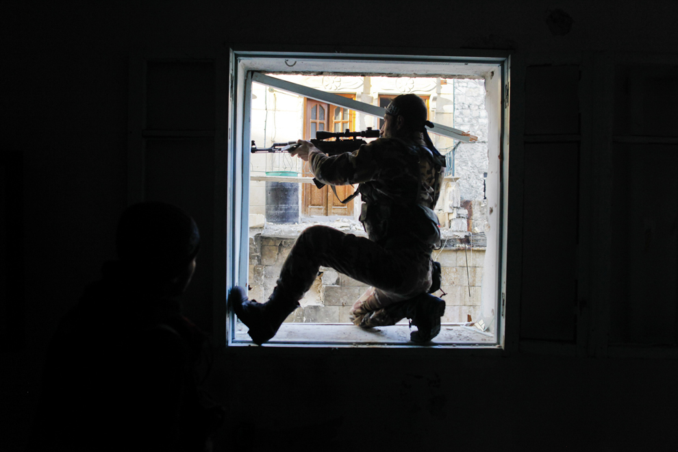 Un membru al Liwa (brigadă) Saladin, o unitate militară curdă care luptă alături de luptătorii rebeli, ţinteşte către un luptător guvernamental în cartierul asediat Karmel al-Jabl din estul Alepului, joi, 6 decembrie 2012. (Javier Manzano / AFP)