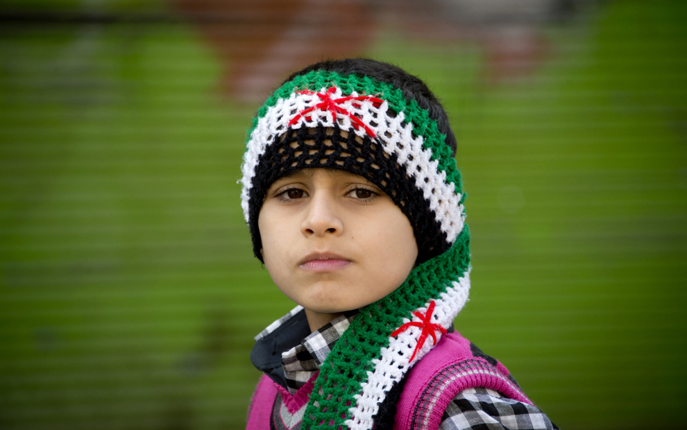 Un băiat sirian, purtând o eşarfă în culorile naţionale siriene din perioada pre-Baath, priveşte spre cameră în oraşul nordic Darkush, vineri, 14 decembrie 2012. (Odd Andersen / AFP)