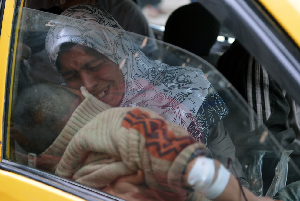 O femeie siriană, aflată într-un taxi, în apropierea unui spital din oraşul nordic Alep, plânge în timp ce îşi ţine in braţe fiul rănit în timpul unui bombardament al forţelor guvernamentale, vineri, 8 februarie 2013. (Aamir Qureshi / AFP)