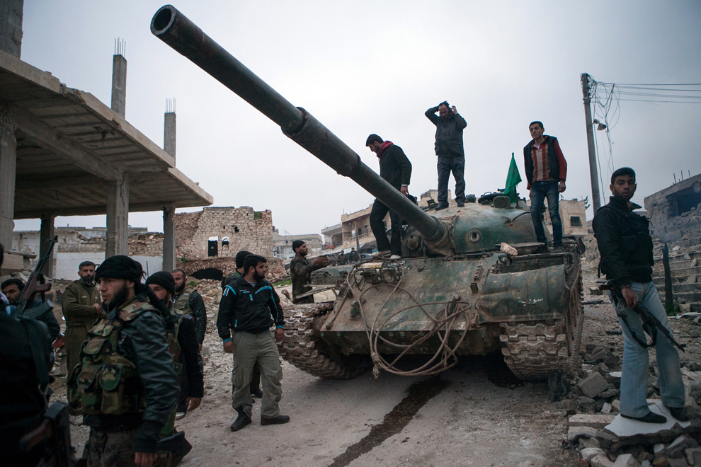 Mai mulţi rebeli sirieni se strâng în jurul unui tanc T-72, capturat cu doua luni în urmă de la forţele guvernamentale, în satul Kfarruma, din provincia Idlib, aflată lângă graniţa cu Turcia, duminică, 10 februarie 2013. (Daniel Leal-Oliva / AFP)
