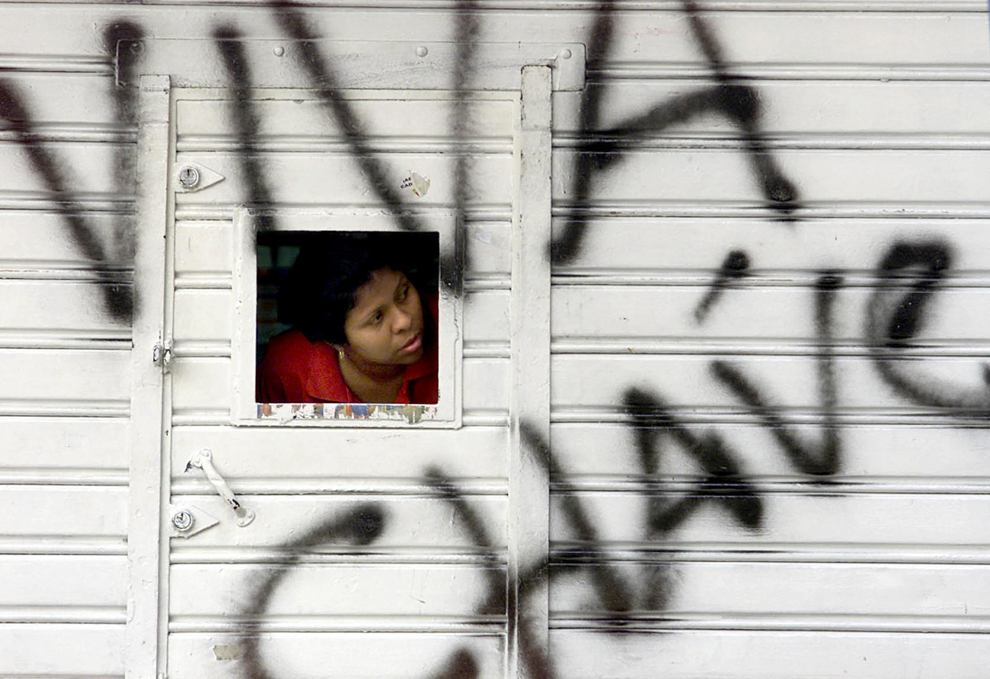 O angajată  a unui magazin închis se uita pe o stradă din Caracas, luni 15 aprilie 2002. Sute de magazine au fost jefuite peste noapte, dupa ce preşedintele venezuelean Hugo Chavez a revenit la putere. 