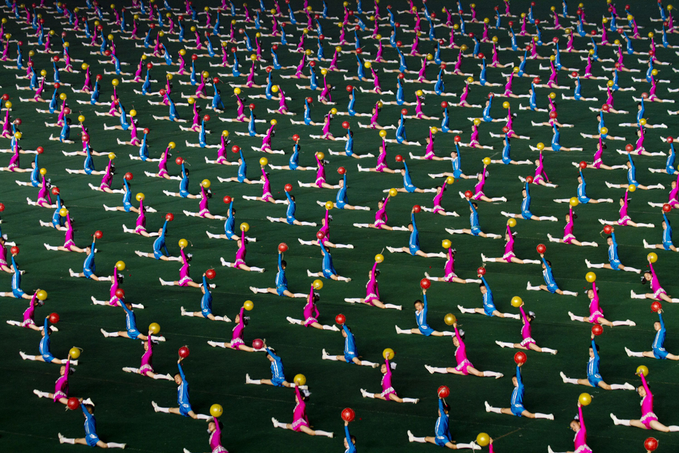 Mii de elevi din Phenian execută elemente de gimnastică, având mingi multicolore, în timpul unui spectacol de masă denumit Arirang, în Phenian, august 2011.  
