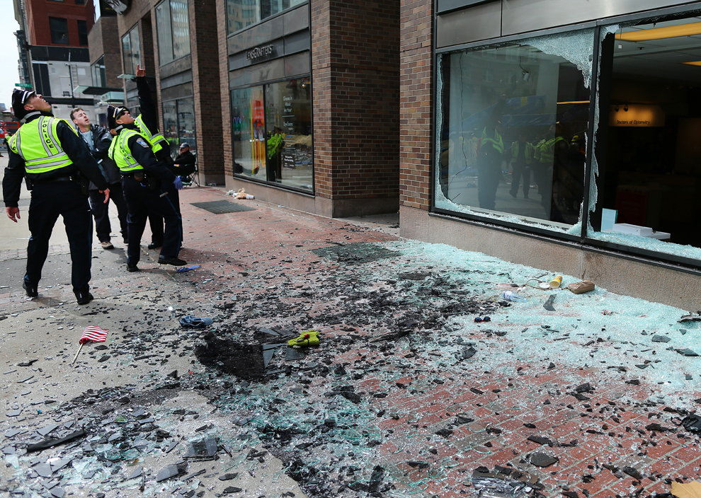Membri ai poliţiei din Boston privesc către locul primei explozii de pe strada Boylston, aproape de linia de sosire a celui de-al 117-lea Maraton al oraşului Boston, luni, 15 aprilie 2013.  