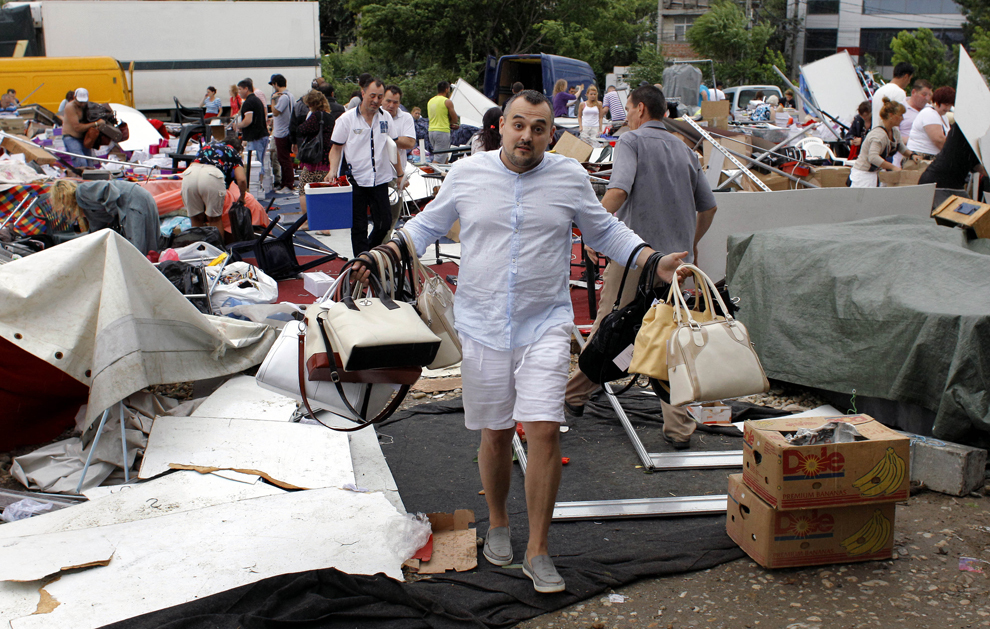 Un bărbat ţine în mâini mai multe produse strânse dintre resturile unui cort prăbuşit în zona Baba Novac din Bucureşti, joi, 23 mai 2013. Construcţia, ce adăpostea un târg de haine şi încălţăminte, s-a prăbuşit din cauza unei furtuni puternice. 