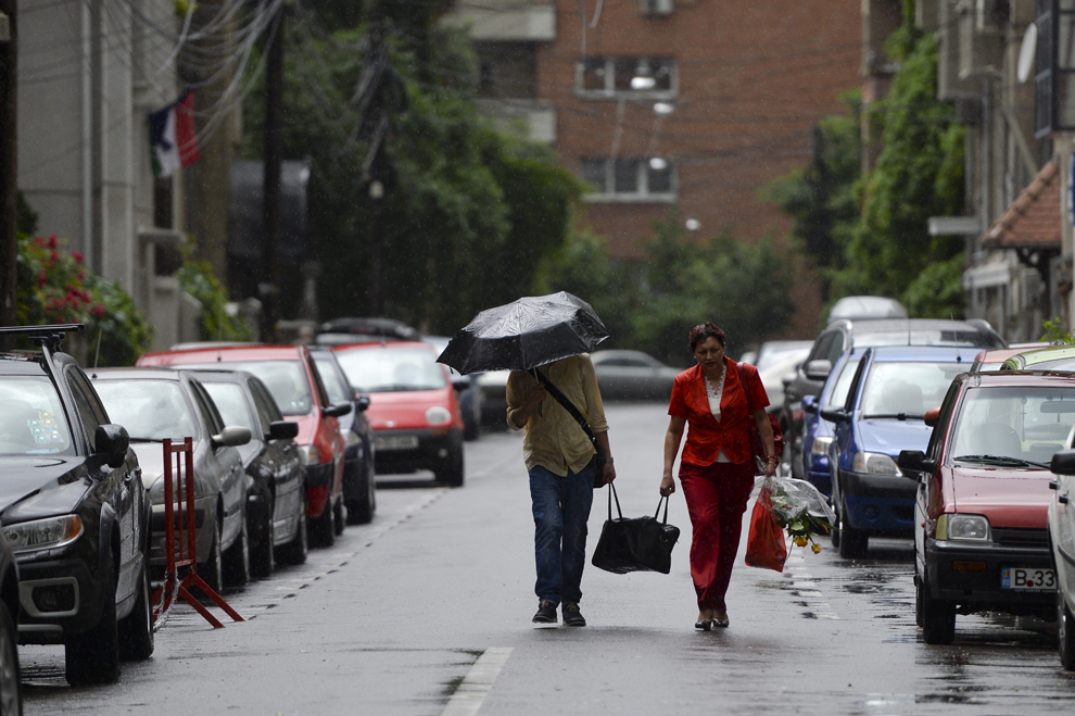 Două persoane transportă un bagaj în timpul unei furtuni, pe o stradă din Bucureşti, joi, 23 mai 2013. 