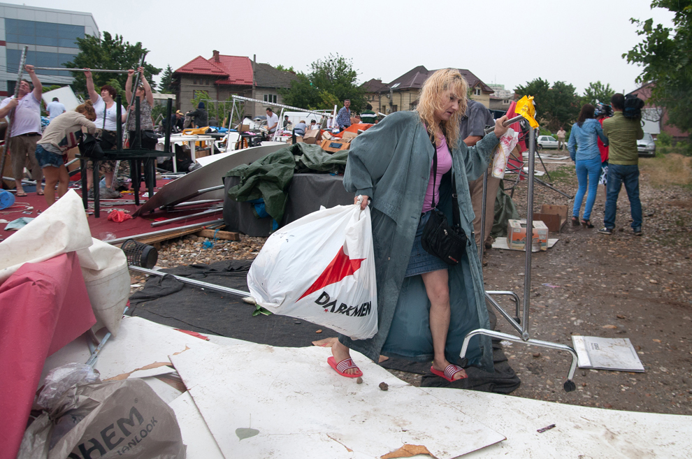O femeie duce o plasă cu produse strânse din resturile unui cort prăbuşit în zona Baba Novac din Bucureşti, joi, 23 mai 2013. Construcţia, ce adăpostea un târg de haine şi încălţăminte, s-a prăbuşit din cauza unei furtuni puternice. 