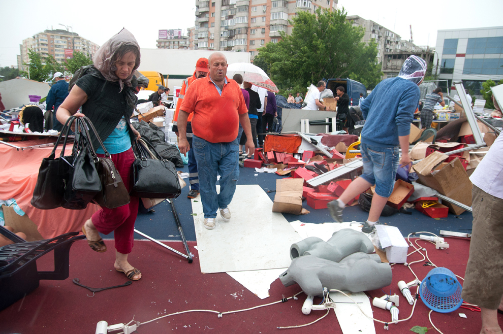 Mai mulţi comercianţi îşi strâng marfa dintre resturile unui cort prăbuşit, în zona Baba Novac din Bucureşti, joi, 23 mai 2013. Construcţia, ce adăpostea un târg de haine şi încălţăminte, s-a prăbuşit din cauza unei furtuni puternice. 