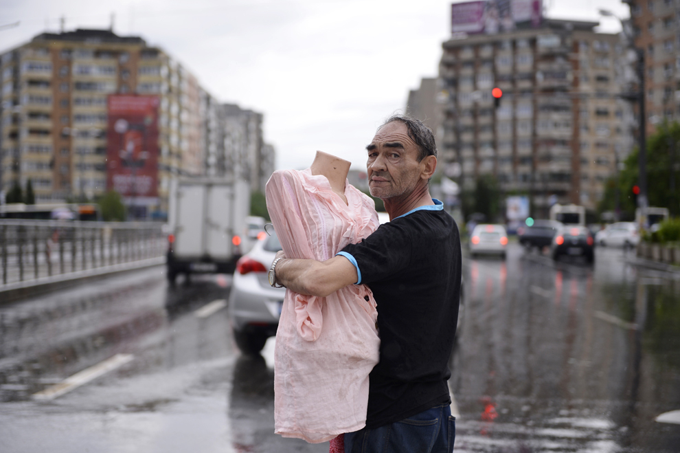 Un bărbat ţine în braţe un manechin, în apropierea unui cort prăbuşit în zona Baba Novac din Bucureşti, joi, 23 mai 2013. Construcţia, ce adăpostea un târg de haine şi încălţăminte, s-a prăbuşit din cauza unei furtuni puternice. 