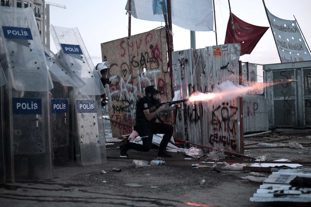 Un poliţist trage cu o armă cu gaze lacrimogene către protestatarii din Piaţa Taksim, în Istanbul, marţi, 11 iunie 2013. 