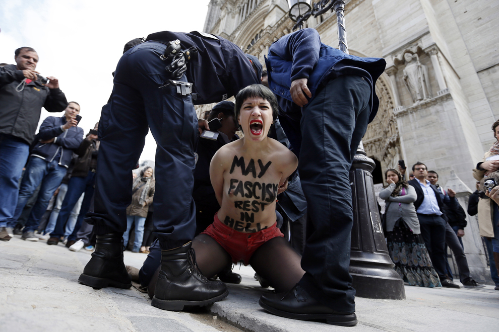 O membră a grupului Femen purtând pe piept textul “Fasciştii să se odihnească în iad” este arestată de poliţie după ce a luat parte la un protest organizat în catedrala Notre Dame din Paris, miercuri, 22 mai 2013. 