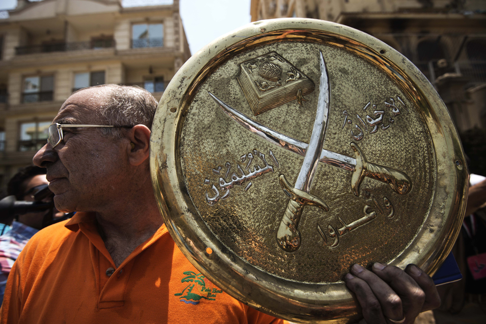 Un bărbat ţine în mână o placheta cu emblema Fraţiei Musulmane (Muslim Brotherhood), ce a fost luată de pe sediul incendiat al partidului, în districtul Moqattam din Cairo, Egipt, luni, 1 iulie 2013. 