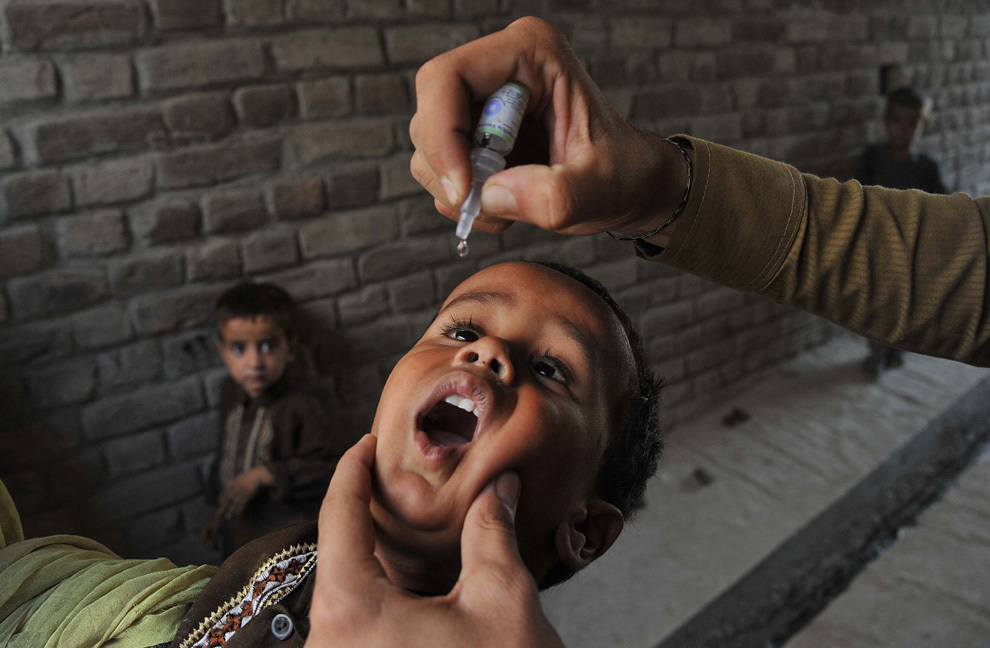 Un asistent medical afgan administrează unui copil un vaccin antipoliomielitic, în cadrul unei campanii de vaccinare în Jalalabad, Afganistan, luni, 26 august 2013. 
