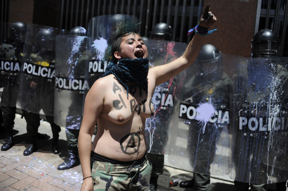 O femeie cu corpul pictat strigă lozinci în faţa unui cordon de poliţişti, în timpul unui protest de susţinere a fermierilor columbieni, în Bogota, Columbia, joi, 29 august 2013. 