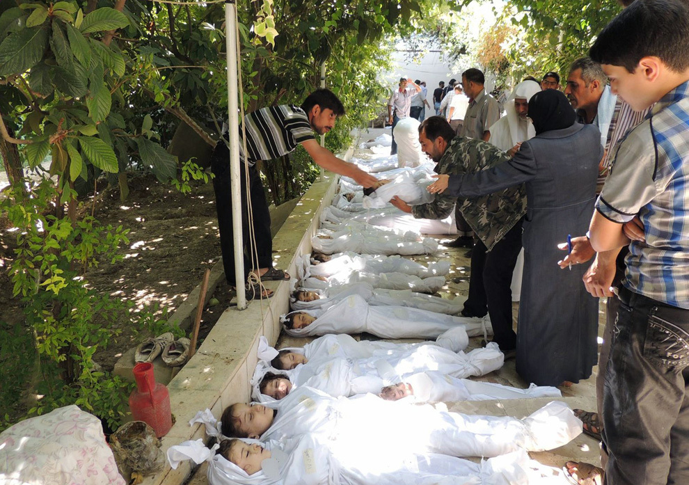 Un bărbat ridică corpul unui copil dintr-un rând de victime, despre care rebelii sirieni susţin ca au decedat în urma unui presupus atac cu arme chimice efectuat de forţele proguvernamentale, în Damasc, miercuri, 21 august 2013. 