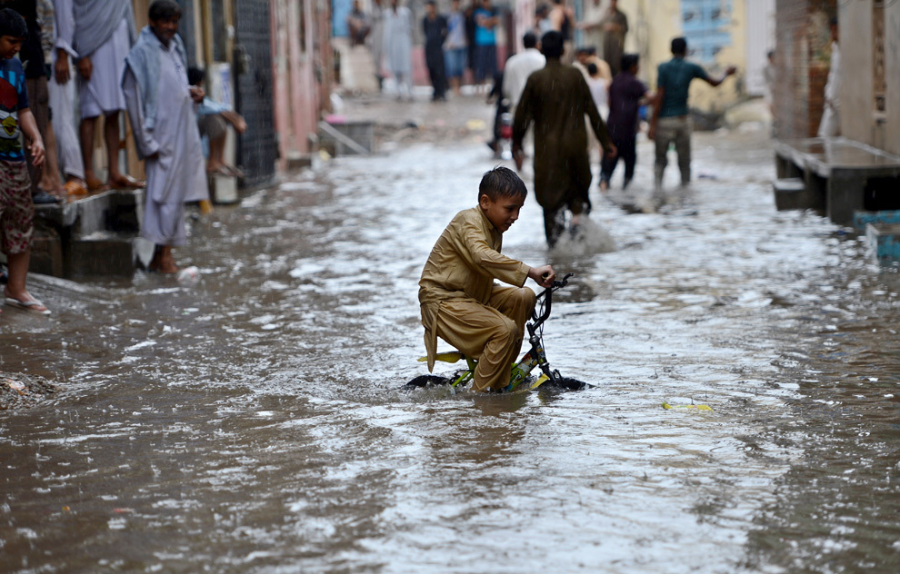 Un băiat pakistanez se plimbă cu bicicleta pe o stradă inundată după o ploaie torenţiala, în Rawalpindi, marţi,  13 august 2013. 