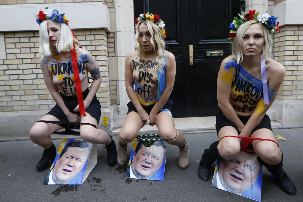 Lidera grupului feminist FEMEN, Inna Shevchenko (C) împreună cu două activiste se prefac că urinează pe fotografii ale preşedintelui Viktor Yanukovych, în faţa ambasadei Ucrainei la Paris, duminică, 1 decembrie 2013.