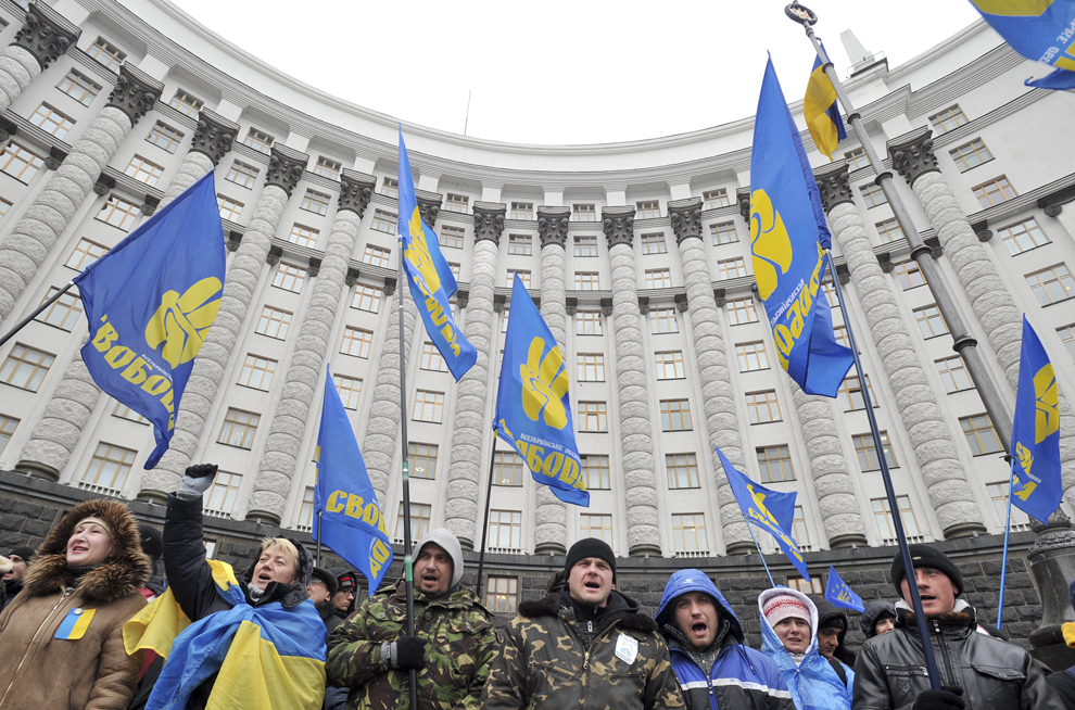 Protestatari Pro-UE, ce ţin în mâini steagul opoziţiei lui Svoboda, blochează intrarea în clădirea Guvernului din Kiev, vineri, 6 decembrie 2013.