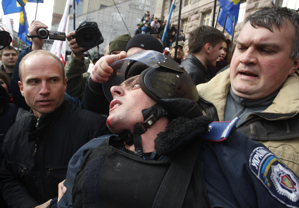 Activişti trag de casca unui jandarm în încercarea de a intra în clădirea primăriei din Kiev, miercuri, 2 octombrie 2013.