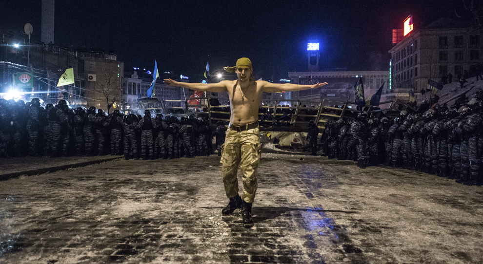 Un protestatar stă în mijlocul forţelor de ordine ce urmează să lanseze un atac asupra baricadelor ridicate de manifestanţi, în piaţa Independenţei din Kiev, miercuri, 11 decembrie 2013.