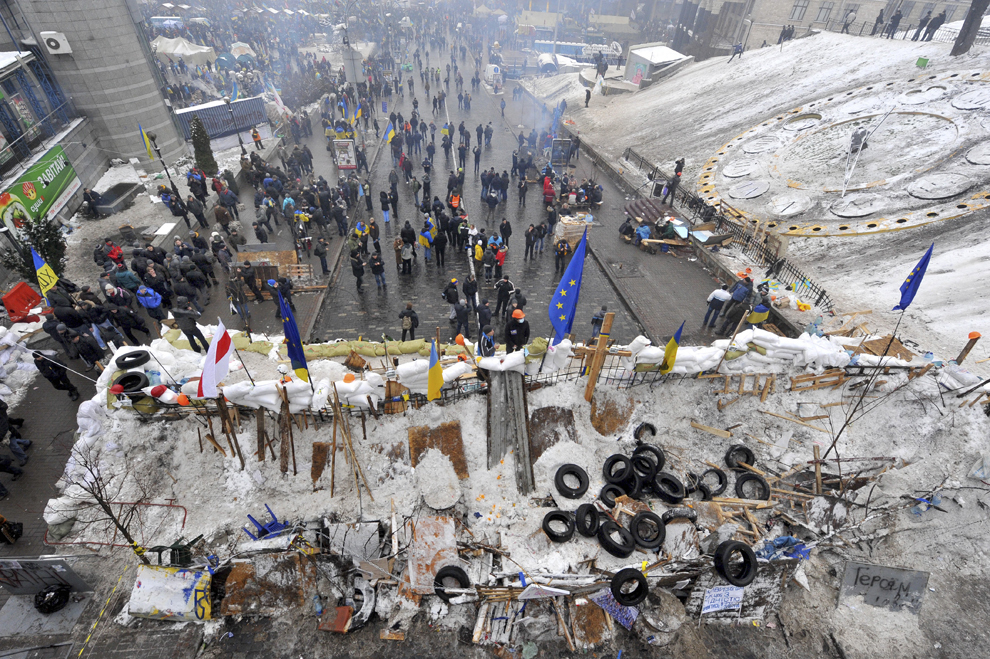 Persoane trec pe langă o baricadă ridicată, în piaţa Independenţei din Kiev, joi, 12 decembrie 2013.