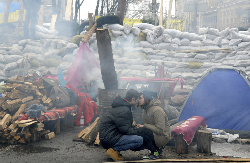 Doi tineri asteaptă langă o baricadă ridicată în piaţa Independenţei din Kiev, joi, 12 decembrie 2013.