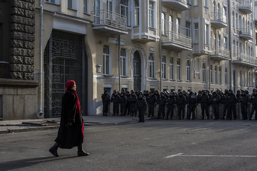 O femeie trece pe lângă un cordon de jandarmi ce păzesc palatul prezidenţial din Kiev, miercuri, 4 decembrie 2013.