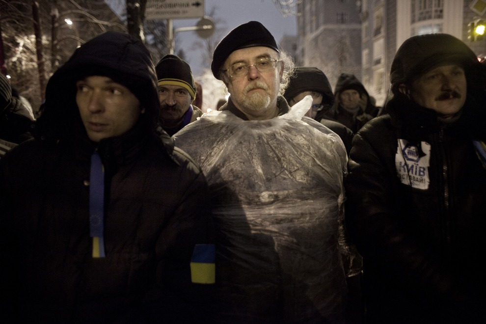 Un grup de protestatari privesc către trupele Berkut ce păzesc palatul prezidenţial din Kiev, luni, 9 decembrie 2013.