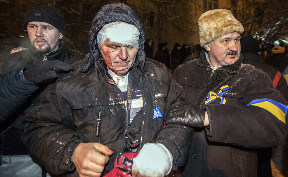 Persoane ajută un protestatar rănit, după o ciocnire cu forţele de ordine ucrainiene, în faţa palatului prezidenţial din Kiev, marţi, 10 decembrie 2013.