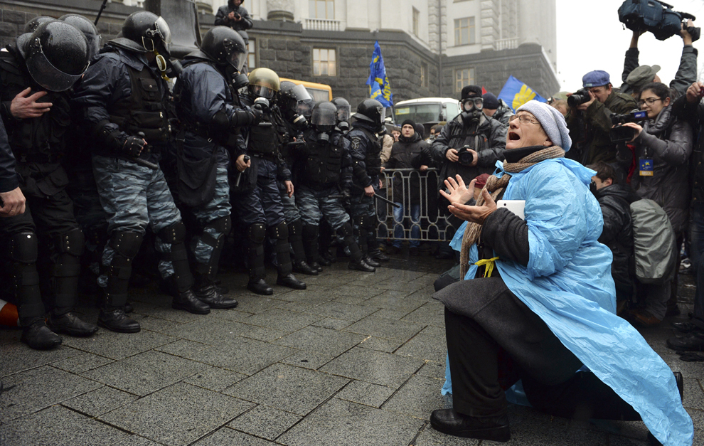 O femeie îngenunchează în faţa forţelor de ordine, în timpul unei demonstraţii Pro-Vest, în faţa Guvernului din Kiev, luni, 25 noiembrie 2013.