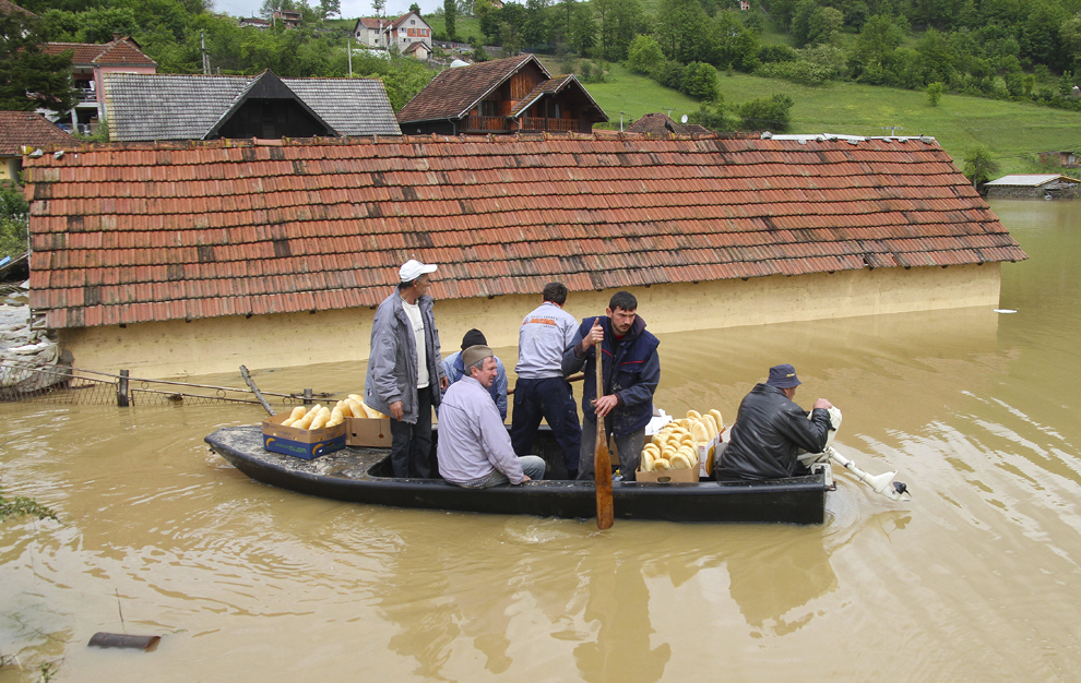Localnici se deplasează cu ajutorul unei bărci pentru a căuta supravieţuitori pe o stradă inundată din Pozega, aflat la aproximativ 200 de km sud-vest de Belgrad, Serbia, vineri, 17 mai 2014.