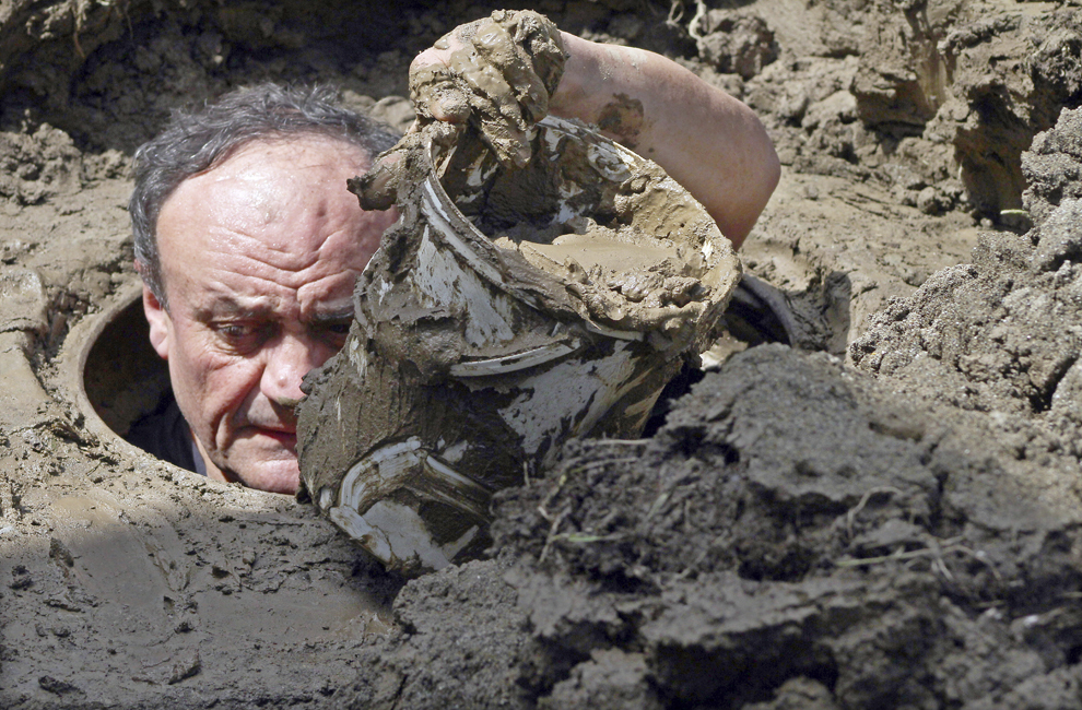 Un bărbat îndepartează, cu ajutorul unei galeţi, namol dintr-un puţ inundat, în Bajina Basta, 160 de km sud-est de Belgrad, Serbia, luni, 19 mai 2014.