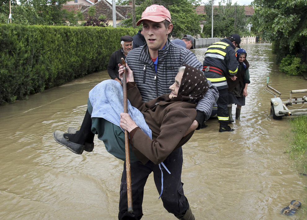Un salvator sârb ţine în braţe o femeie in vârstă, dupa ce a evacuat-o din casa inundată, din oraşul Obrez, în apropiere de Vavarin, la sud de Belgrad, Serbia, vineri, 17 mai 2014.