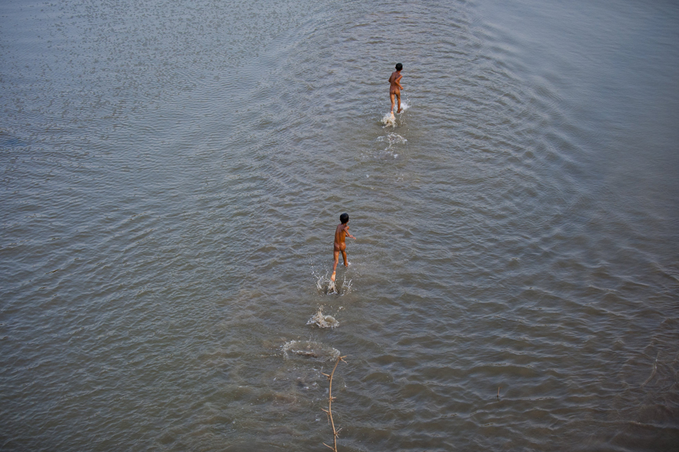 Copii aleargă pe malul unui râu în satul Lar Po, în apropiere de Monywar, Mianmar, marţi, 20 mai 2014.