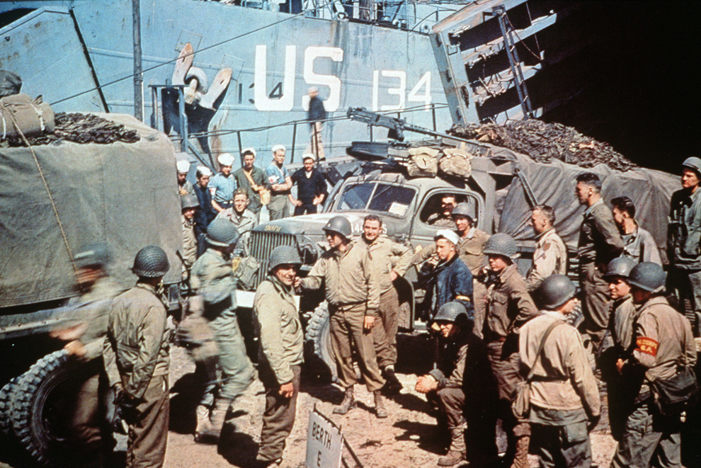 Soldaţi americani debarcă camioane militare pe plaja din Normandia la scurt timp după Ziua Z.