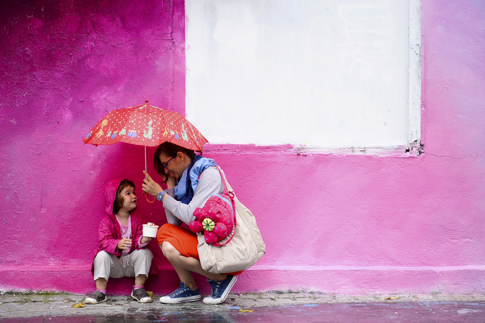 O fetiţă şi mama ei se feresc de ploaie, în cadrul evenimentului "Street Delivery" din Bucureşti, sâmbătă, 14 iunie 2014.