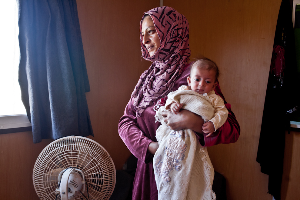 Femeia siriancă îşi ţine bebeluşul în braţe în containerul familiei din tabăra de refugiaţi Za’atari, Iordania. Copilul de două săptămâni, născut în Za’atari, este cel mai tânăr refugiat din tabără.