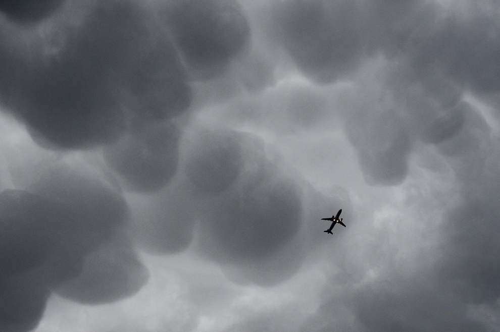 Un avion poate fi văzut printre formaţiuni noroase, în Bucureşti, miercuri, 25 iunie 2014.