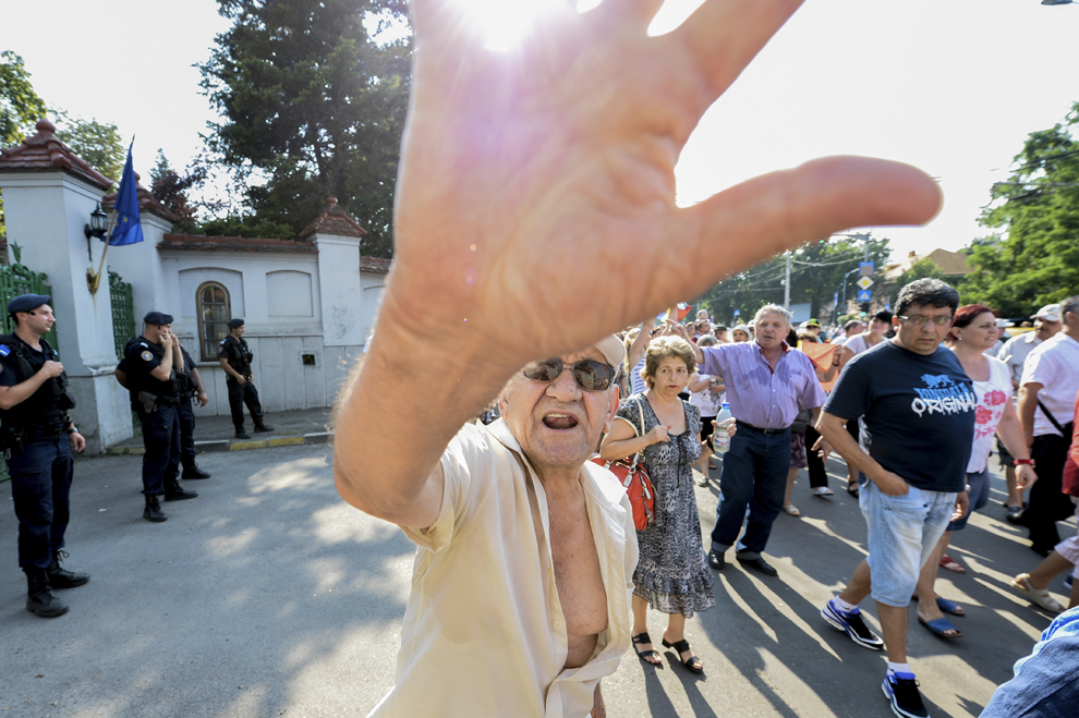 Un bărbat trage de aparatul de fotografiat şi adresează injurii presei, în timpul unei manifestaţii pro-Antena 3, în faţa Palatului Cotroceni din Bucureşti, duminică, 10 august 2014.