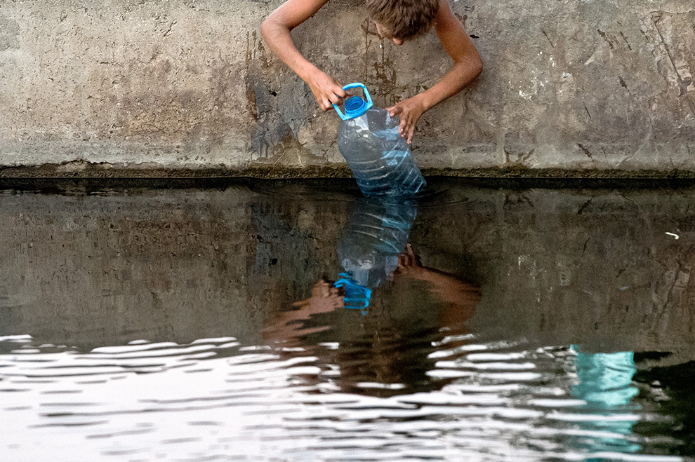 Un copil colectează apă din râul Dâmboviţa din Bucureşti, miercuri, 13 august 2014.