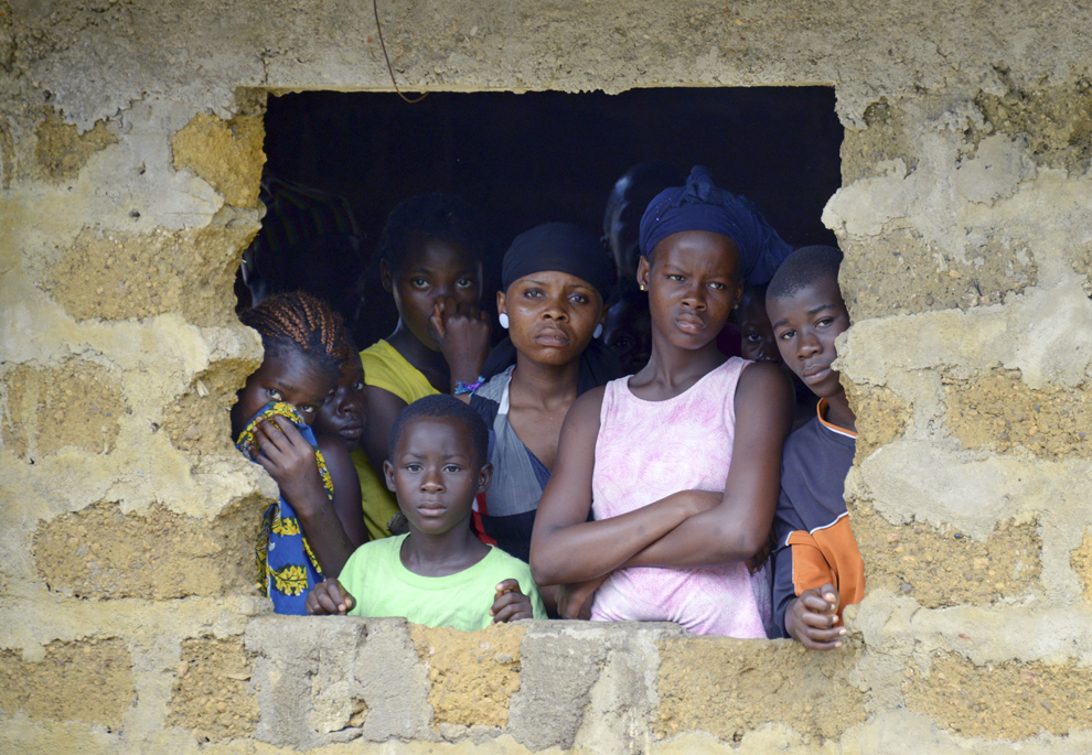 Vecinii unei persoane decedate în urma infectării cu virusul Ebola privesc echipajul medical al Crucii Roşii Liberiene venit să care defunctul, joi, 4 septembrie 2014.