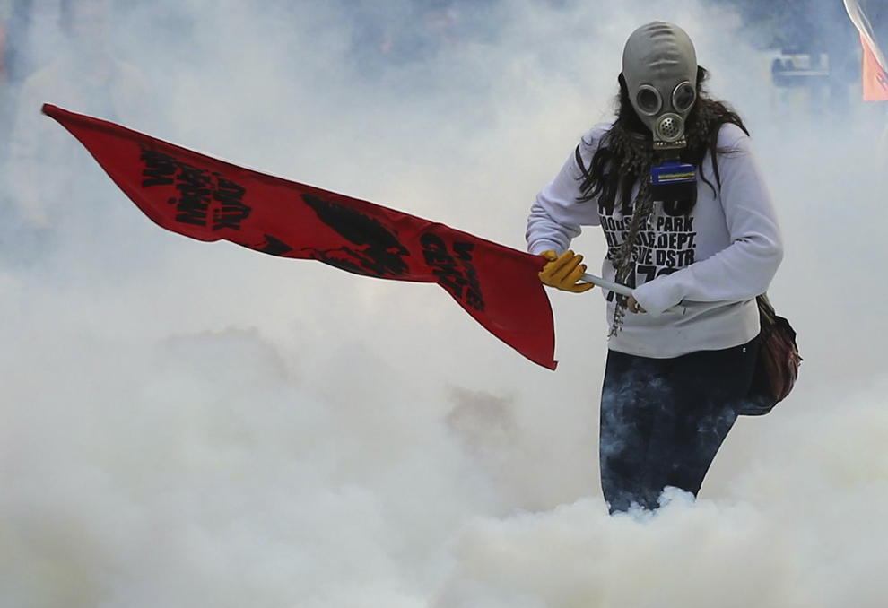 O persoană ţine un steag în timp ce poliţia foloseşte gaze lacrimogene şi tunuri cu apă asupra protestatarilor ce protestează împotriva atacurilor lansate de Statul Islamic (IS), în Ankara, Turcia, marţi, 7 octombrie 2014.